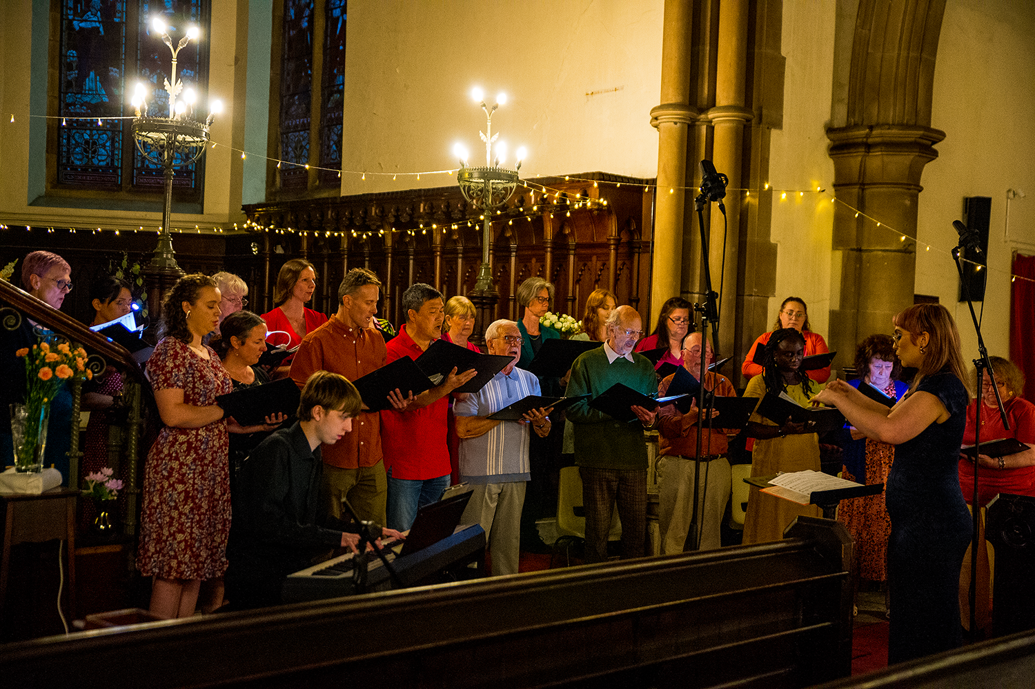 Vocal Sounds choir in full voice beneath the stained glass windows